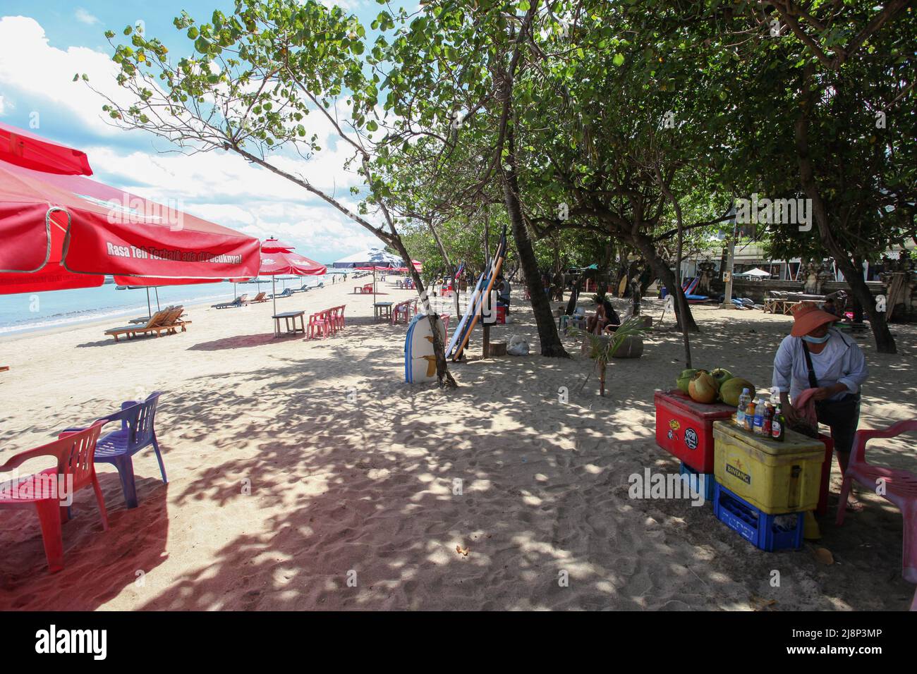 Kuta Beach Szene in Bali, Indonesien im März 2022 während der Pandemie mit wenigen Touristen, Getränkeverkäufern, Sonnenschirmen und einem ruhigen Strand. Stockfoto