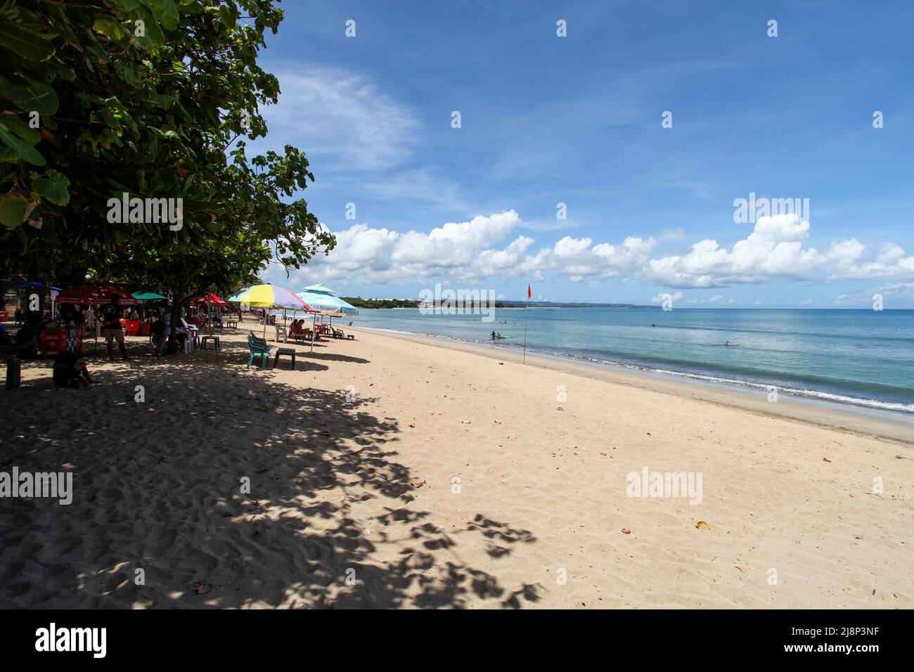 Kuta Beach Szene in Bali, Indonesien im März 2022 während der Pandemie mit wenigen Touristen, Getränkeverkäufern, Sonnenschirmen und einem ruhigen Strand. Stockfoto