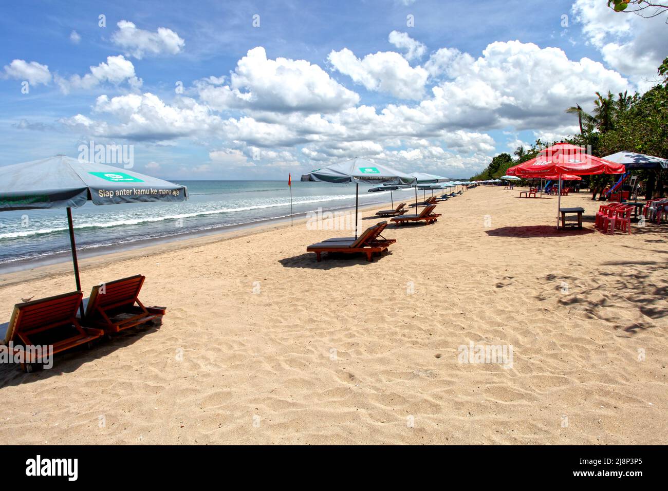 Kuta Beach Szene in Bali, Indonesien im März 2022 während der Pandemie mit wenigen Touristen, Getränkeverkäufern, Sonnenschirmen und einem ruhigen Strand. Stockfoto