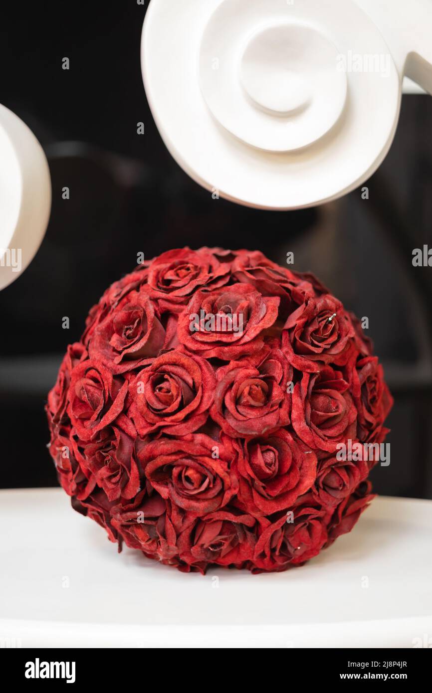 Im Inneren steht eine dekorative Kugel aus roten Rosé-Kelchen. Stockfoto