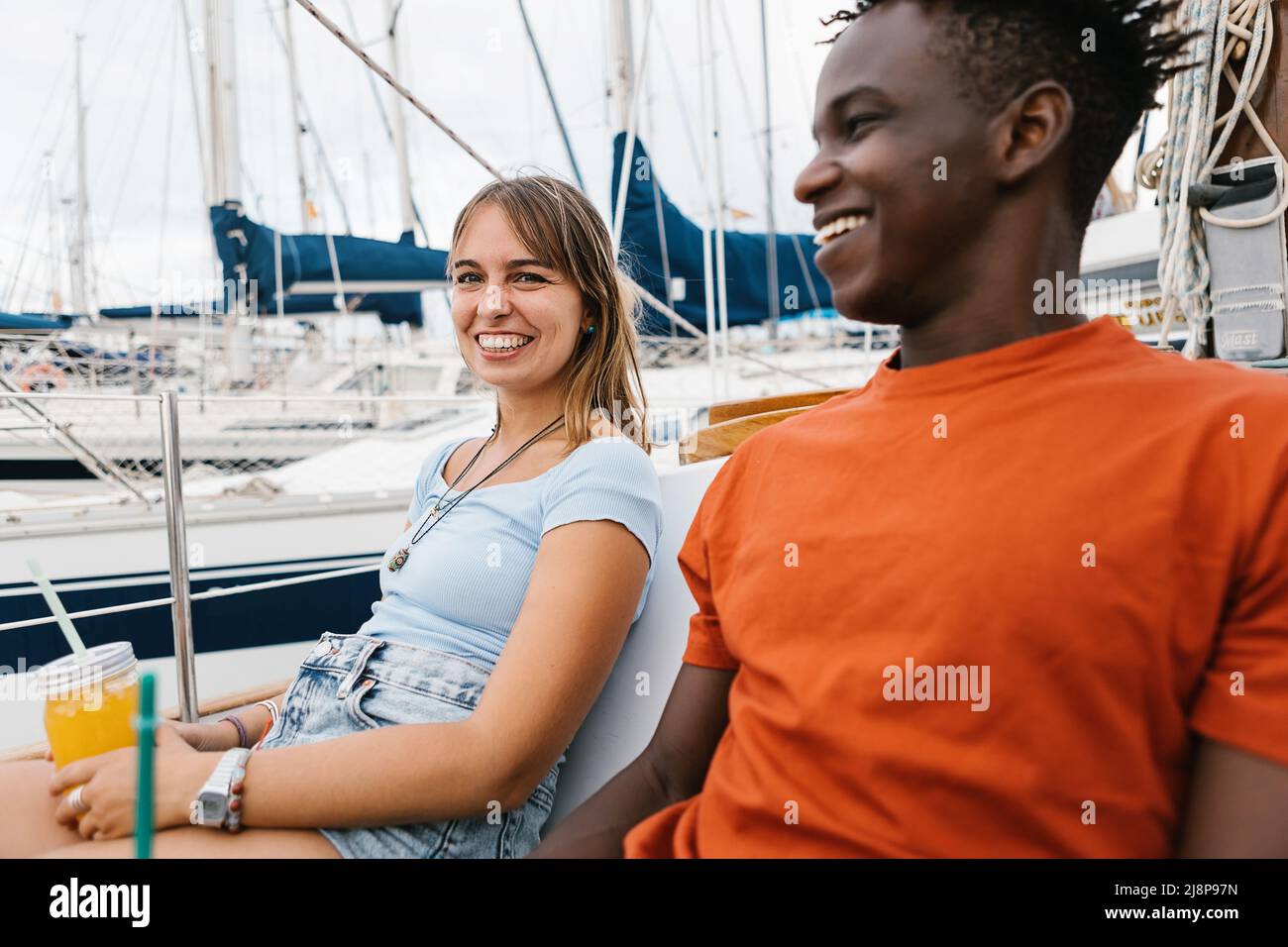 Glückliches multirassisches Paar, das Spaß im Freien auf einem Boot hat. Stockfoto