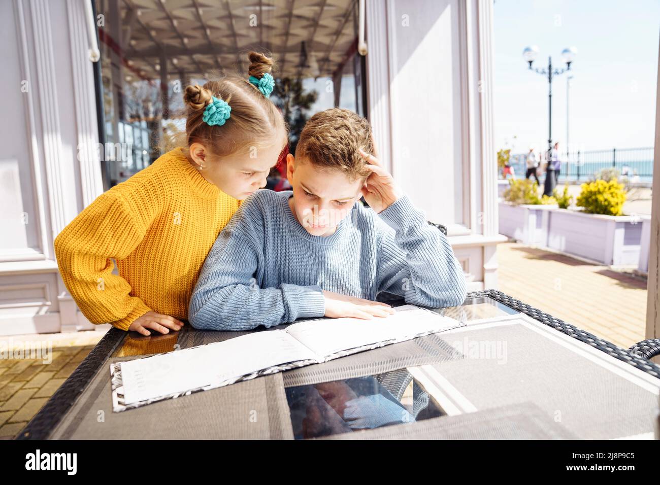 Kinder im Café studieren die Speisekarte, um Pizza zu bestellen. Stockfoto