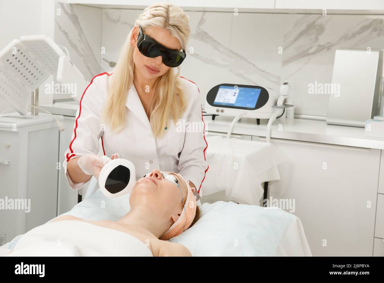 Eine Kosmetologin führt in einer Kosmetologie-Klinik ein Verjüngungsverfahren durch. Laserbehandlung. Stockfoto