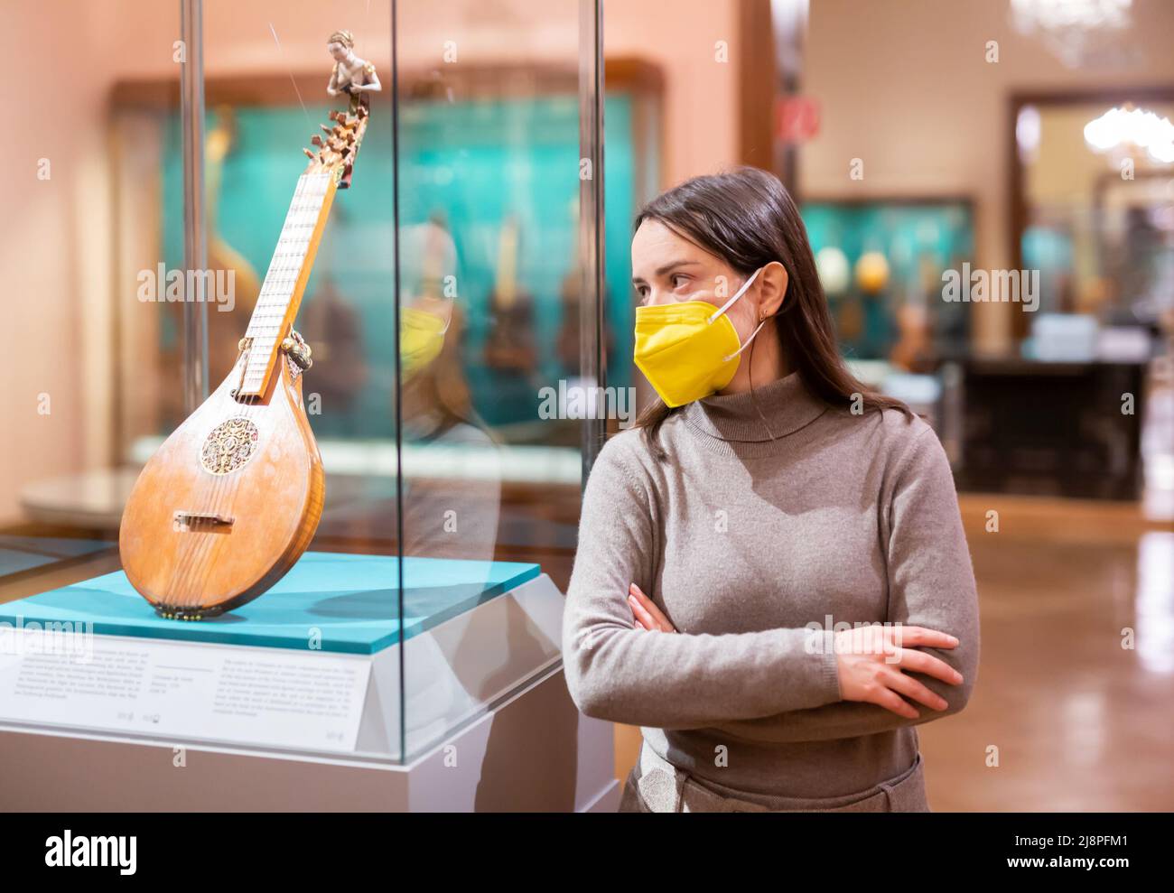 Brunette in Schutzmaske Besuch Ausstellung von mittelalterlichen Musikinstrumenten Stockfoto