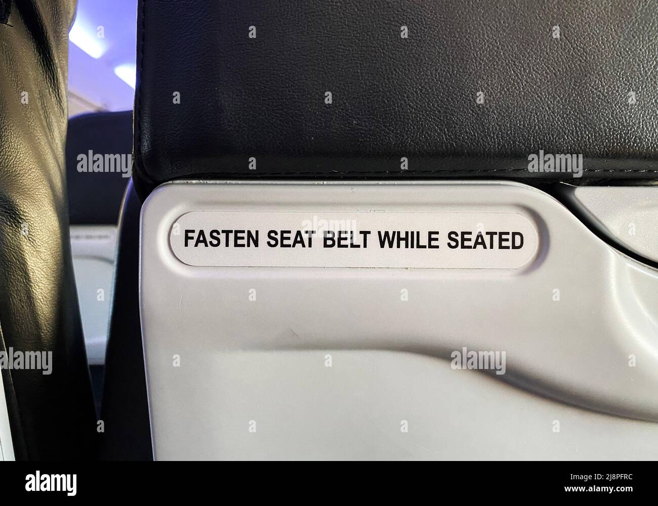 Ein Schild mit der Aufschrift „im Sitzen den Sicherheitsgurt anlegen“ auf einem Flugzeug Stockfoto