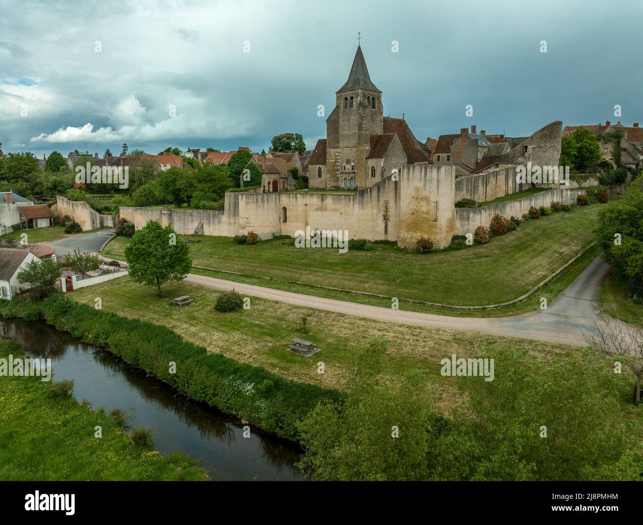 Luftaufnahme von Ainay le Chateau aus dem Osten, kleine mittelalterliche Stadt im Département Allier in Frankreich mit Stadtmauer und Stadttor-Uhrturm bewölktem Himmel Stockfoto