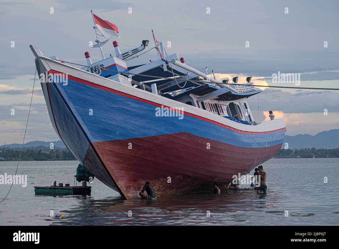 Fischer reinigen das Boot von Austern, die am Rumpf befestigt sind, bevor sie den Rumpf in Kendari lackieren. Fischer in Kendari nutzen die ungünstige Wetterlage, um zum Meer zu fahren, indem sie ihr Fischerboot reparieren und warten. (Foto von Andry Denisah / SOPA Images/Sipa USA) Stockfoto