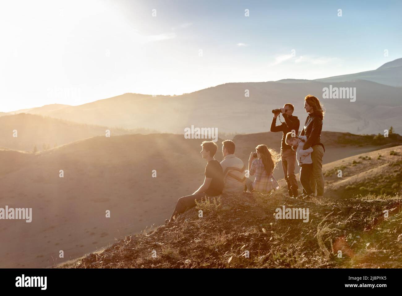Eine große Gruppe junger Menschen entspannen sich in den Sonnenuntergangsbergen Stockfoto