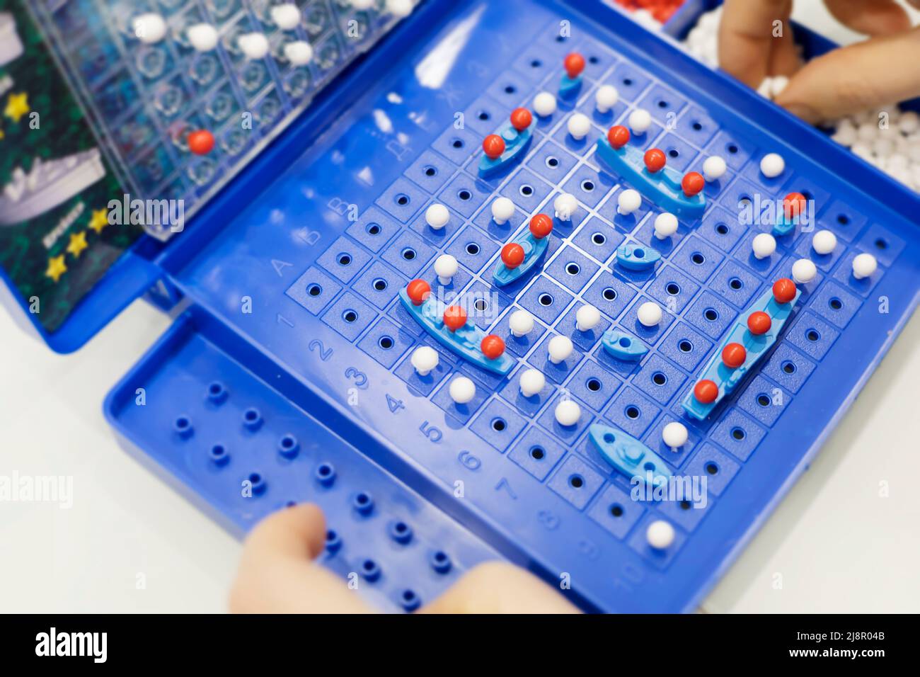 Nahaufnahme von Game-Sea Battle. Spielzeugkriegschiffe und U-Boot werden auf dem Spielfeld platziert. Konzept-Strategie, Denken, Sieg, Niederlage. Stockfoto