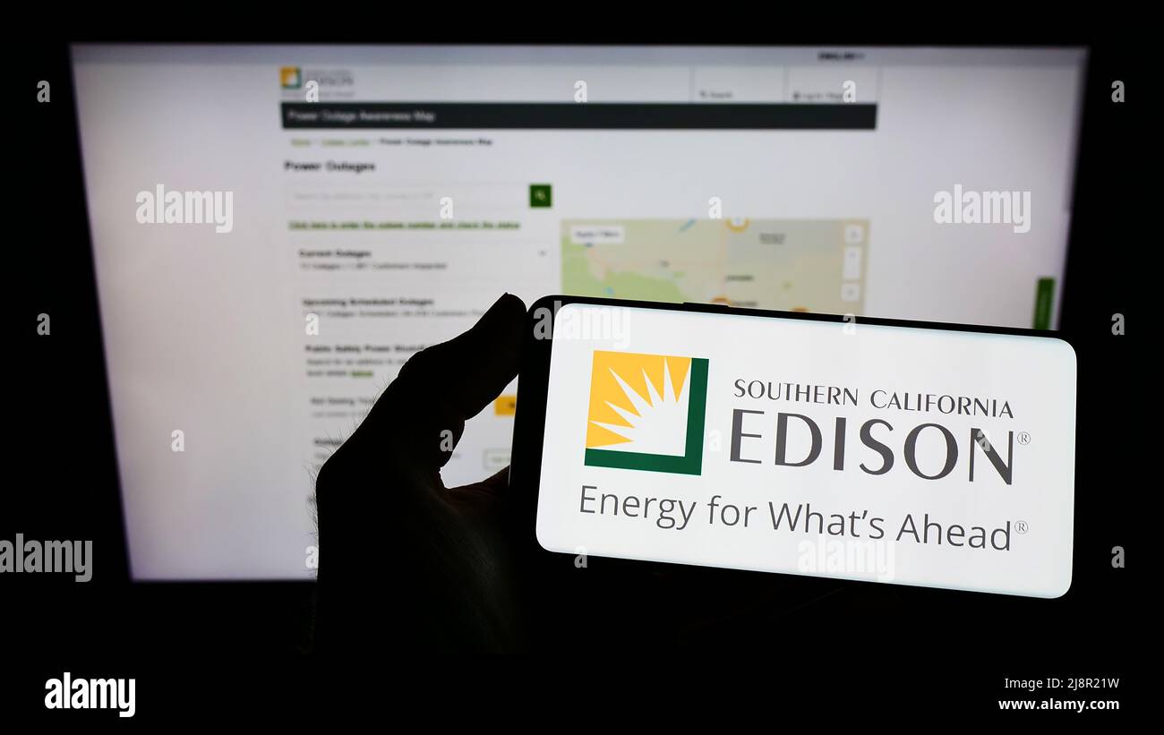 Person mit Mobiltelefon und Logo des US-Unternehmens Southern California Edison (SCE) auf dem Bildschirm vor der Business-Webseite. Konzentrieren Sie sich auf die Telefonanzeige. Stockfoto