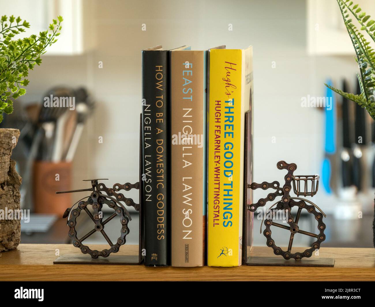 Neuheit Fahrrad-Buchstützen aus einer Fahrradkette, die 3 Kochbücher auf dem Küchenregal unterstützt Stockfoto