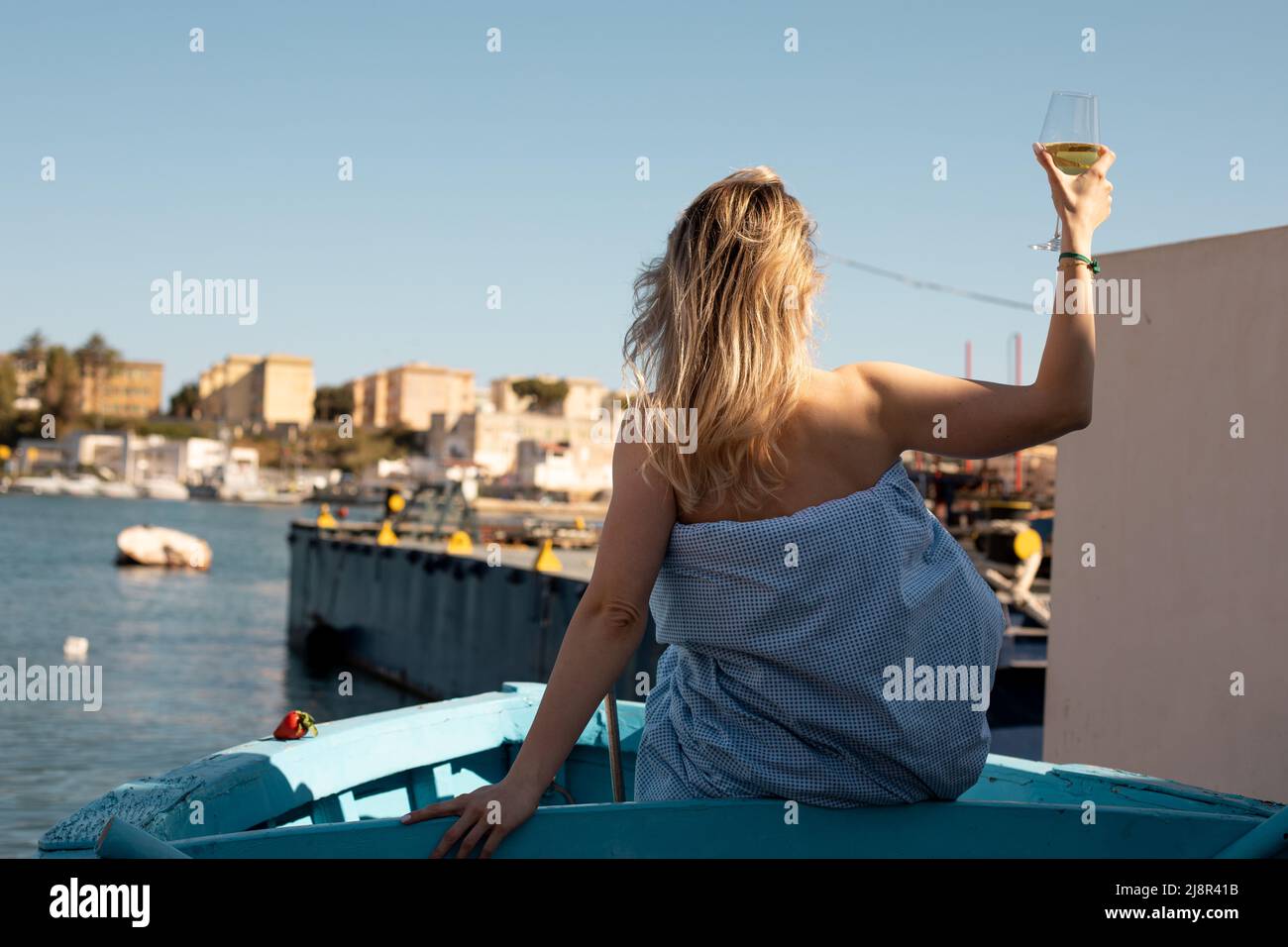 Rückfahrerin mit elegantem Weinglas im Urlaub auf Reisen. Entspannung im Boot. Seehafen, Hafen mit Schiffen Stockfoto