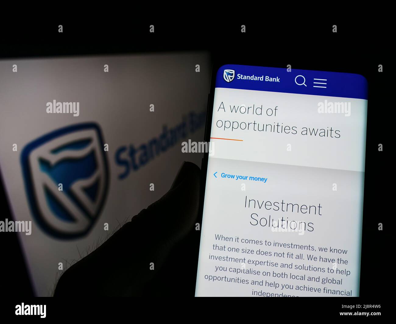 Person mit Mobiltelefon und Webseite des südafrikanischen Unternehmens Standard Bank Group Limited auf dem Bildschirm mit Logo. Konzentrieren Sie sich auf die Mitte des Telefondisplays. Stockfoto