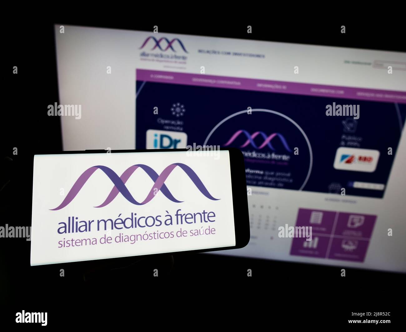 Person, die das Smartphone mit dem Logo des brasilianischen Gesundheitsunternehmens Grupo Alliar auf dem Bildschirm vor der Website hält. Konzentrieren Sie sich auf die Telefonanzeige. Stockfoto