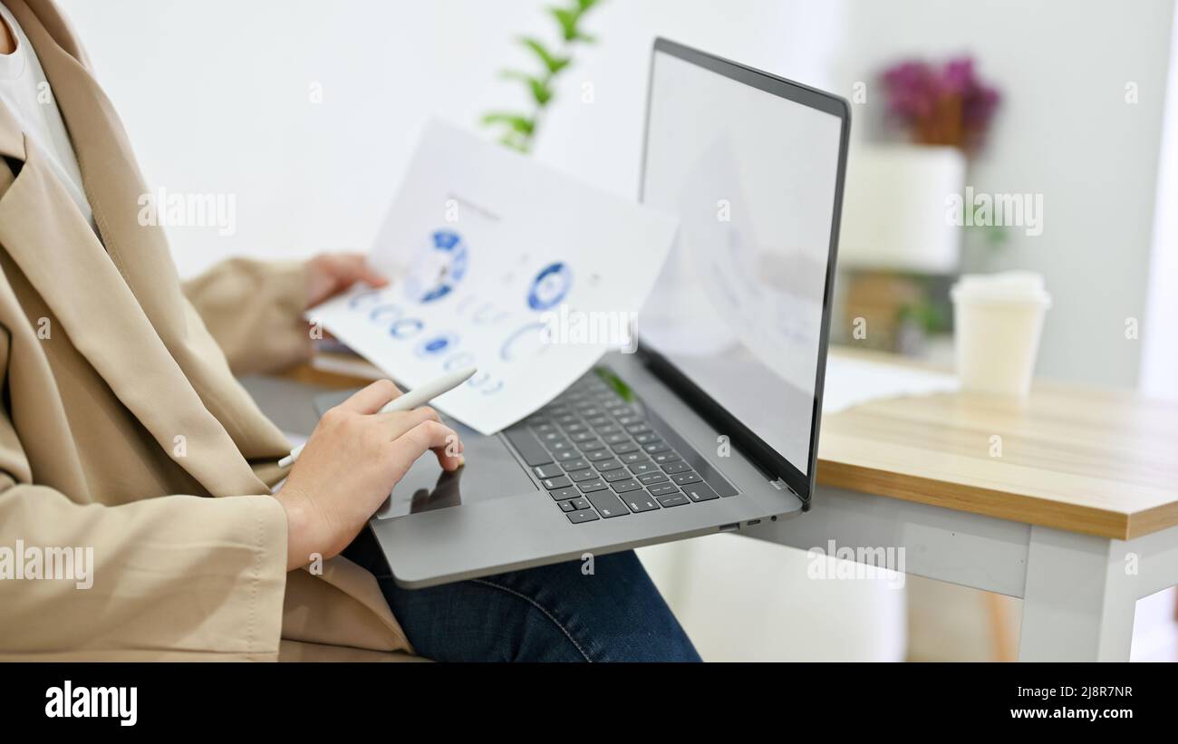 Nahaufnahme, weibliche Millennial-Business-Strategie-Planerin Lesen Sie eine Details über Papierkram und mit Laptop-Computer. Stockfoto