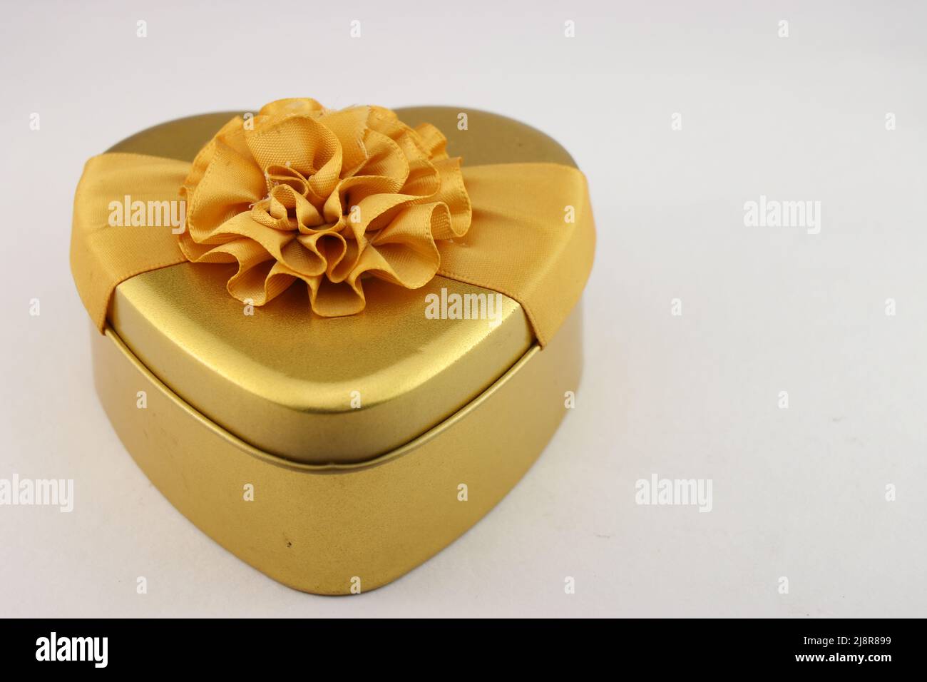 Herzförmige Geschenkbox mit einem schönen Band auf weißem Hintergrund, Geschenkbox für Geburtstage, Valentinstag und andere besondere Ereignisse Stockfoto