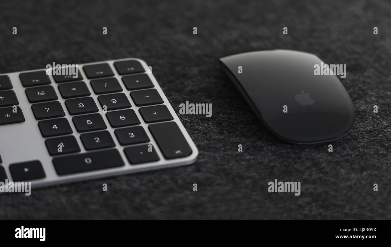 LONDON - 17. MÄRZ 2022: Apple Black Silver Touch id Tastatur und Magic Mouse auf dunklem Schreibtisch Stockfoto