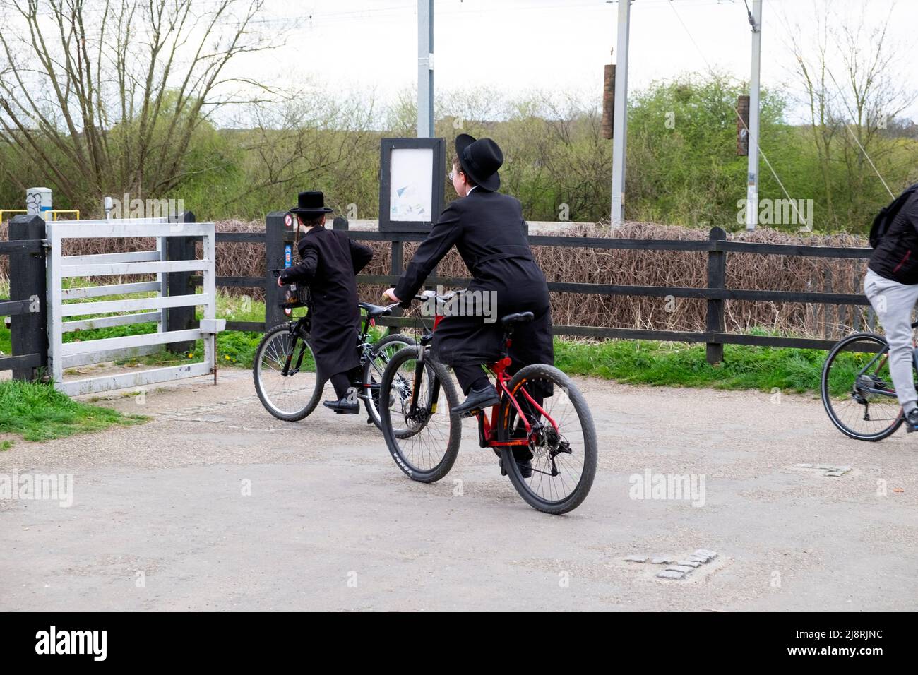 Orthodox-jüdische Jungen auf dem Fahrrad auf dem Radweg durch das Tor im Walthamstow Wetlands Naturschutzgebiet in London, England, Großbritannien, FAHREN KATHY DEWITT Stockfoto
