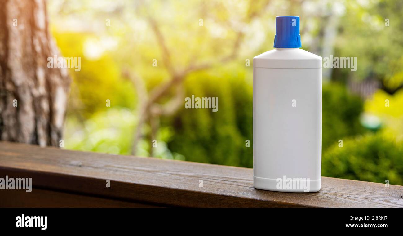 Weiße leere Düngerflasche auf Gartenhintergrund. Banner mit Kopierfläche Stockfoto