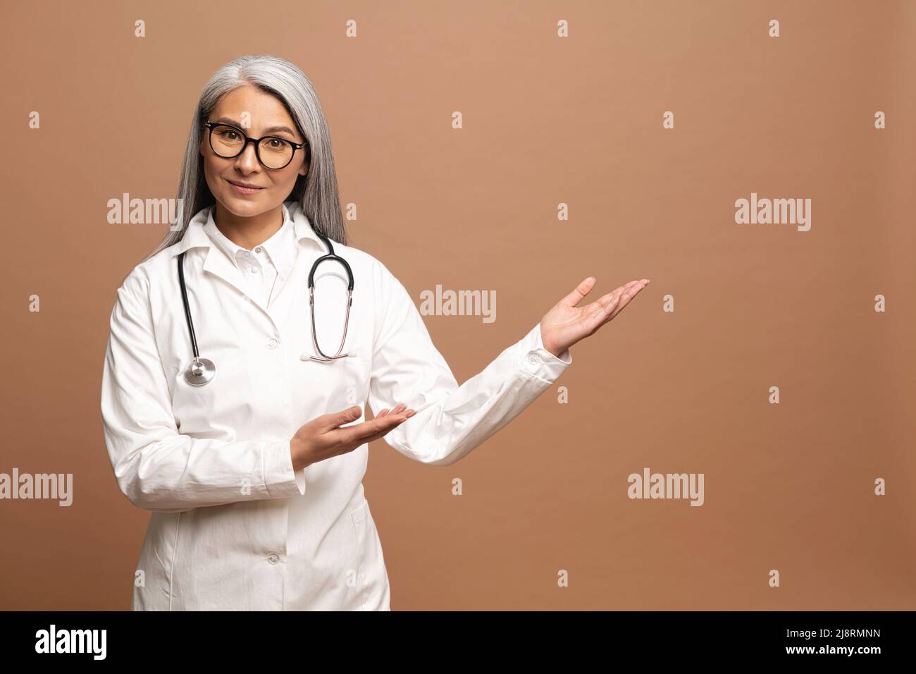 Asiatische charmante Ärztin Pädiatrie, Arzt, Therapeut trägt ein weißes medizinisches Kleid mit einem Stethoskop auf den Schultern zeigt die Hände auf leeren Raum, Mock-up, Kopierer Raum. Gesundheitswesen und Medizin Stockfoto