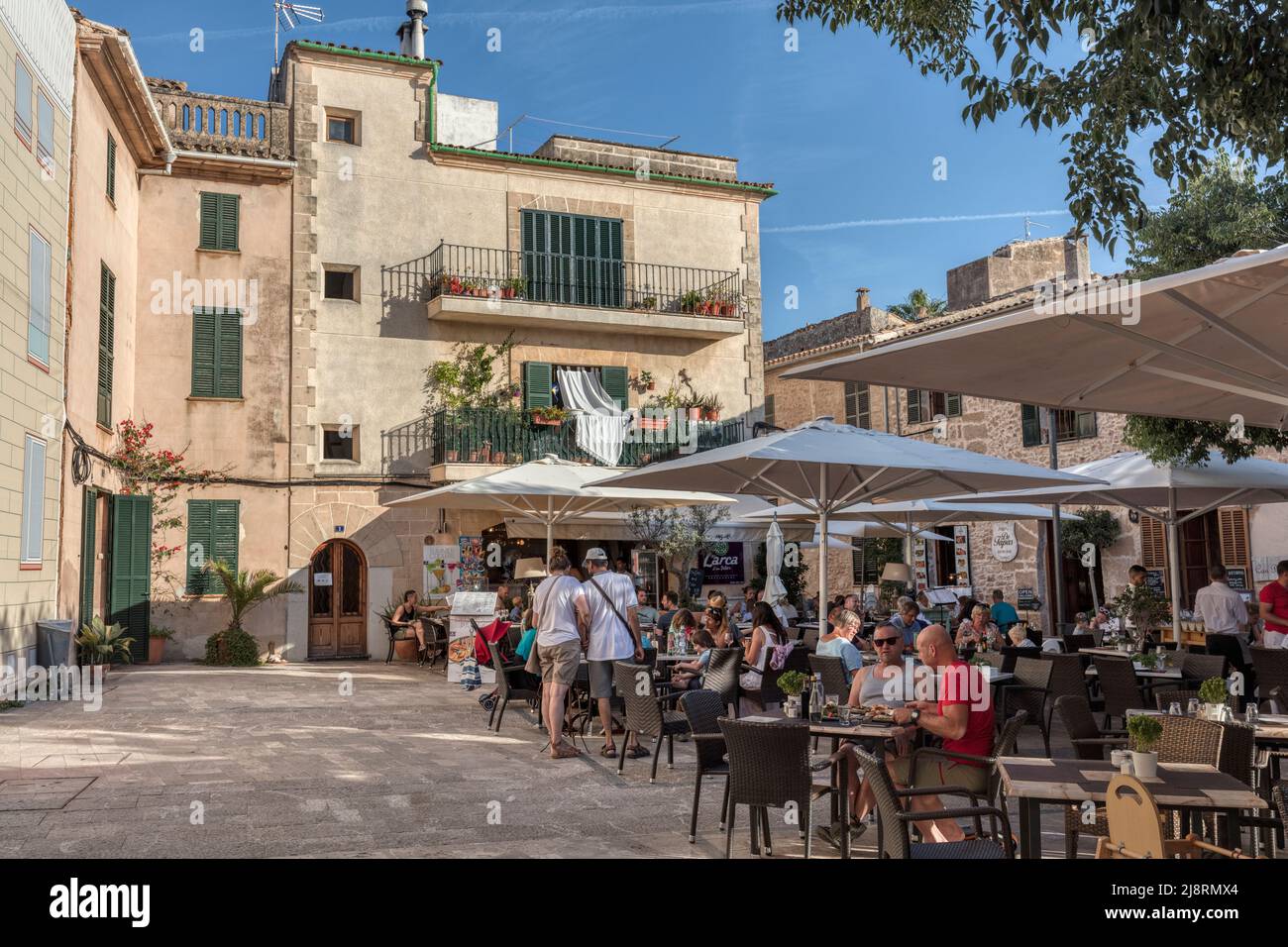 Menschen in Cafés und Restaurants in Placeta de Les Verdure's in der mittelalterlichen Altstadt von Alcudia, Mallorca, Spanien Stockfoto