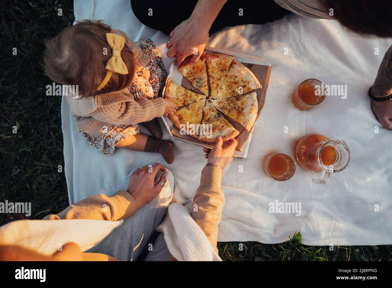 Draufsicht auf die junge Familie Mama Papa und Tochter, die im Freien Picknick machen und Pizza essen Stockfoto