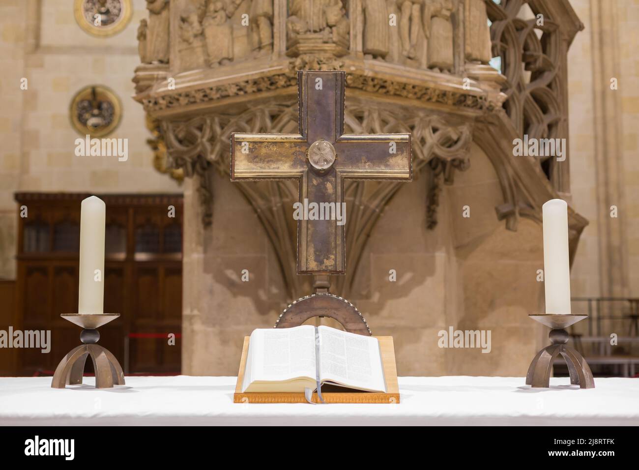 Ulm, Deutschland - 7. Aug 2021: Aufgeschlagene bibel mit einem Kreuz und zwei Kerzen an einem Altar im Ulmer Dom. Stockfoto