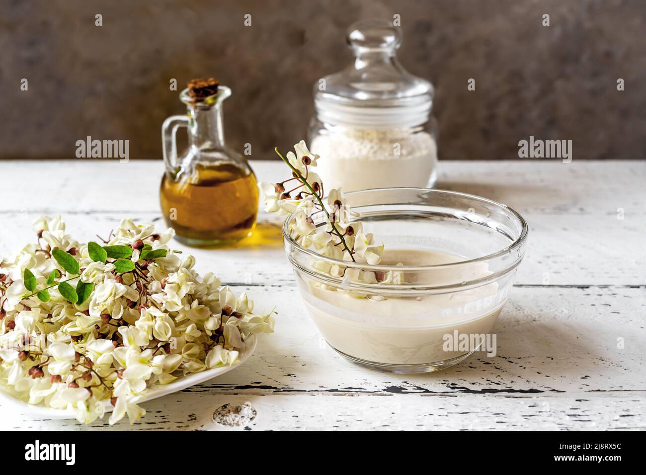 Akazienblumen auf Teller mit Teig und getauchten Zweig zum Kochen fritters Stockfoto