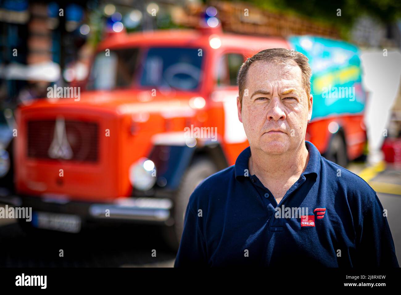 18. Mai 2022, Niedersachsen, Hannover: Mario Kraatz, Landesvorsitzender der Feuerwehrabteilung der Gewerkschaft Verdi, steht während der 24-stündigen Demonstration unter dem Motto "Wahltag ist Zahltag" vor dem niedersächsischen landtag vor einem alten Feuerwehrauto. Neben Mitarbeitern der Berufsfeuerwehr und der Vollzeit-Sicherheitskräfte nehmen auch Beamte aus vielen anderen Bereichen an dem Protest Teil. Unter anderem fordern sie die Wiedereinführung von Urlaubs- und Weihnachtsboni, Bildungsurlaub statt Sonderurlaub und einen kostenlosen c Stockfoto