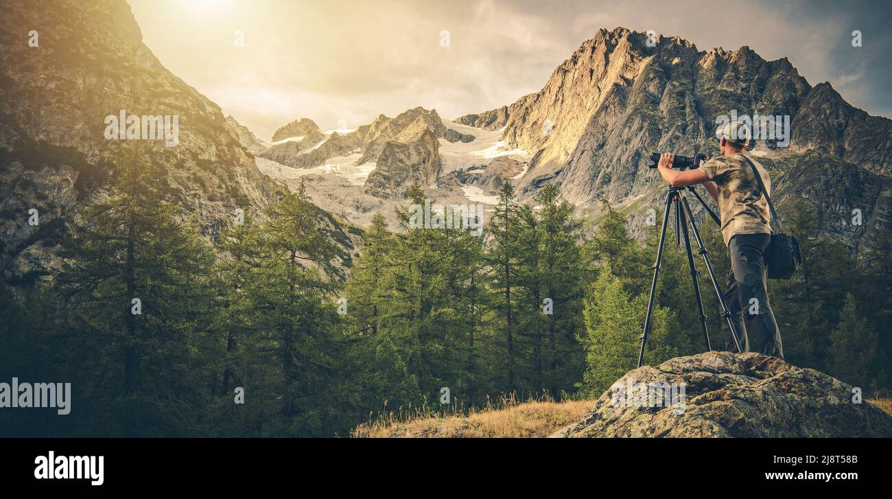 Panoramafoto des kaukasischen Fotografen in seinem 40s Aufnahmen von Landschaftsbildern mit Digitalkamera mit Stativ. Malerische Alpenlandschaft. Stockfoto