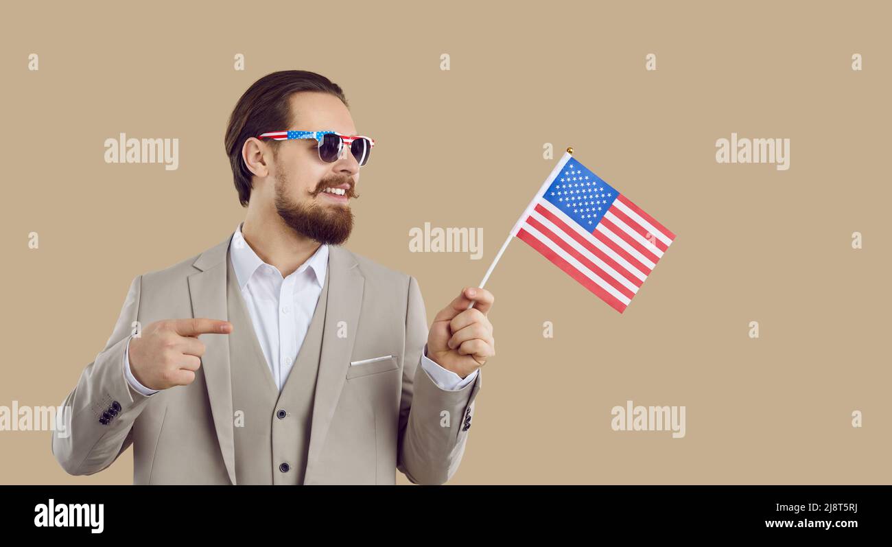 Patriotischer eleganter Mann mit amerikanischer Flagge und Sonnenbrille auf beigem Hintergrund isoliert. Stockfoto