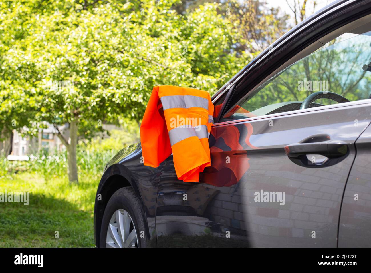 Eine orangefarbene Warnweste hängt am Spiegel eines Pkw. Pannenkonzept,  Pannenhilfe, Probleme Stockfotografie - Alamy