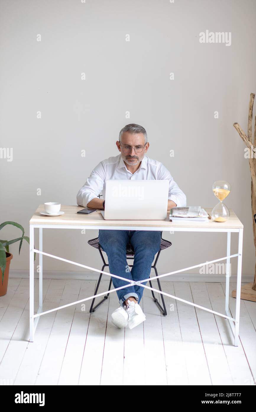 Mann mit Brille, der im Büro am Laptop arbeitet Stockfoto