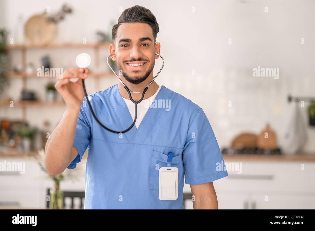 Fröhlicher Arzt, der ein medizinisches Instrument vor der Kamera zeigt Stockfoto