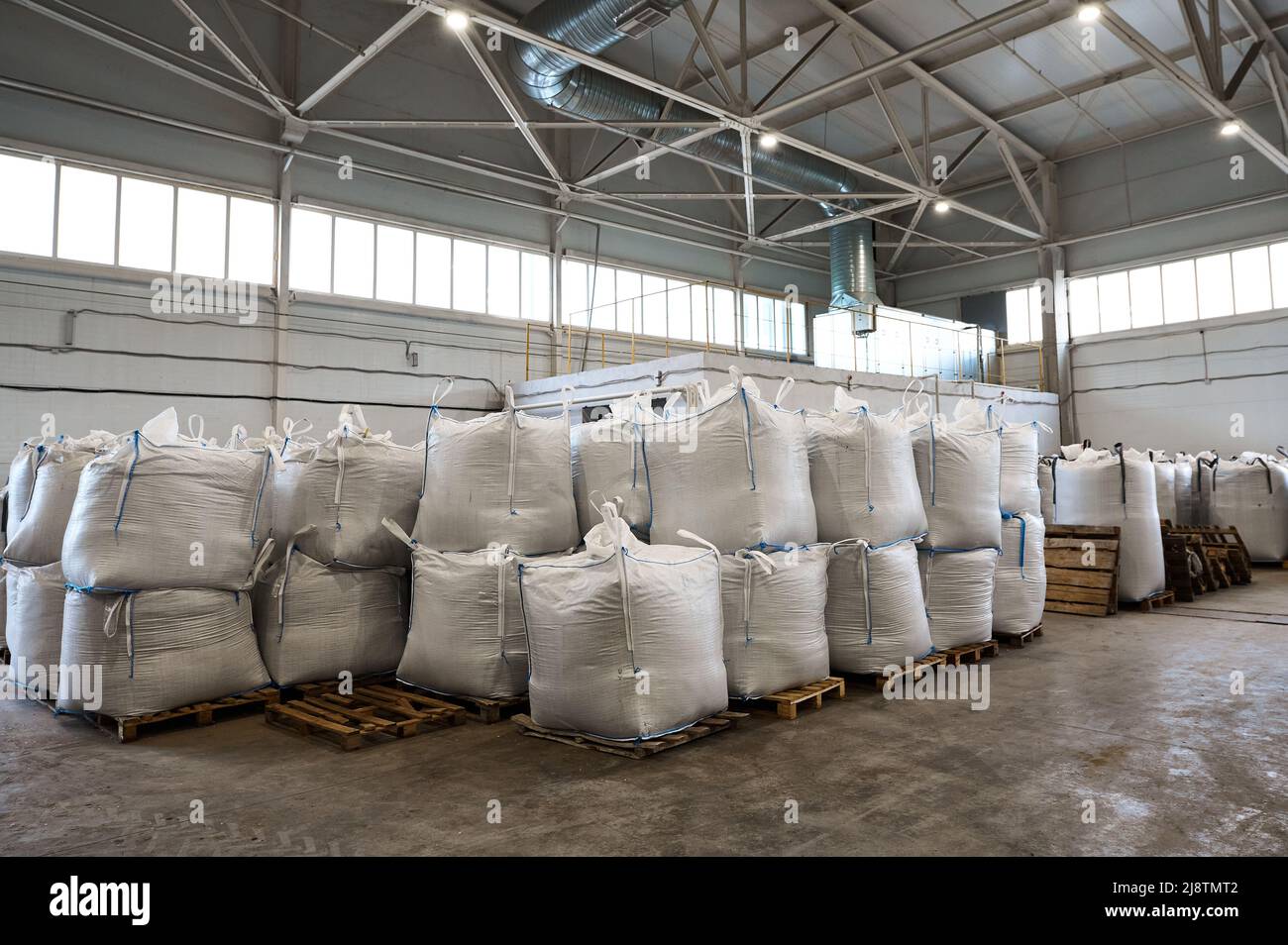 Riesige Plastiktüten mit Produkten auf Paletten in der Recyclingfabrik Stockfoto