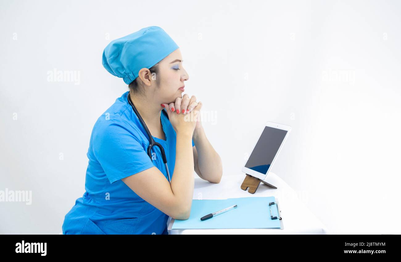 Schöne Frau Labortechnikerin trägt Uniform und blaue OP-Kappe, in Videoanruf, um Ergebnisse zu liefern, auf weißem Hintergrund Stockfoto