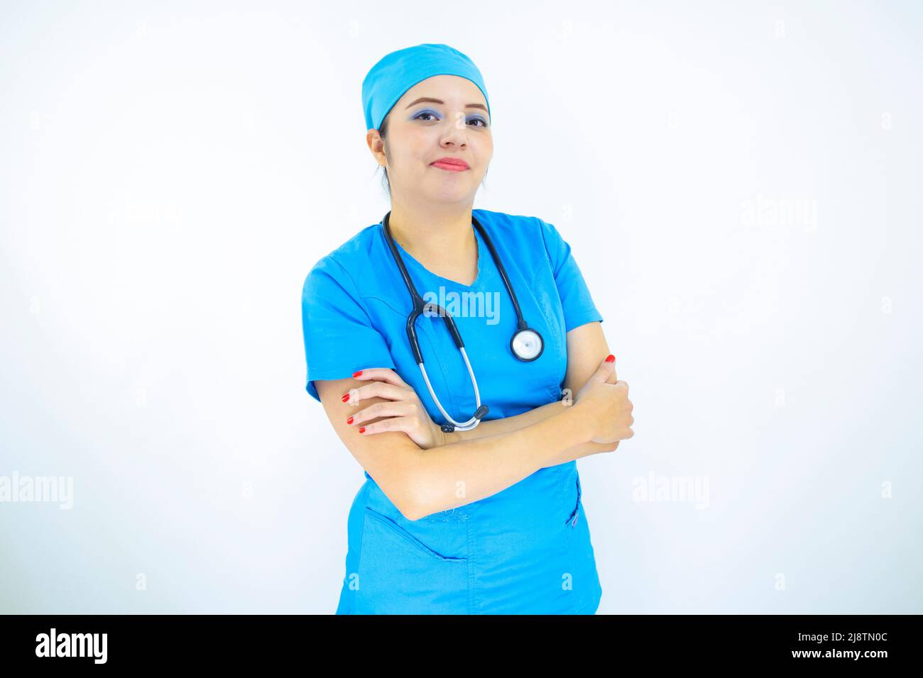 Schöne Ärztin trägt Uniform und blaue OP-Kappe, professionelle Frau mit Stethoskop am Hals auf weißem Hintergrund Stockfoto
