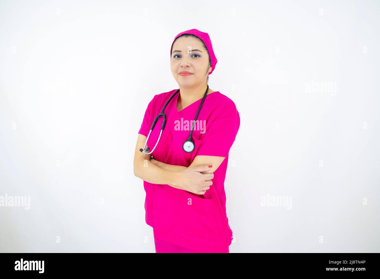 Schöne weibliche medizinische Assistentin trägt Uniform und rosa OP-Kappe, Stethoskop, professionell auf weißem Hintergrund Stockfoto