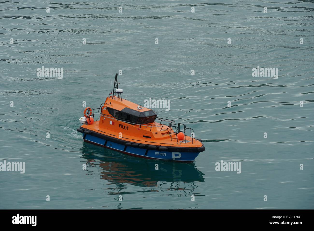 Modernes orangefarbenes Pilotboot mit blauem Rumpf, das sich dem Frachtschiff im Hafen von Koper, Slowenien, nähert. Stockfoto