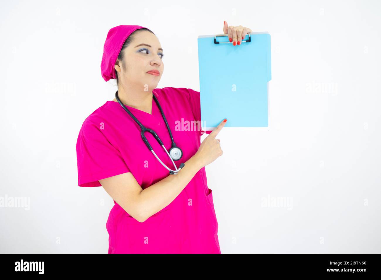 Schöne Frau medizinische Assistentin, trägt Uniform und rosa OP-Kappe, Stethoskop, zeigt auf Zwischenablage mit Ergebnissen, auf weißem Hintergrund Stockfoto