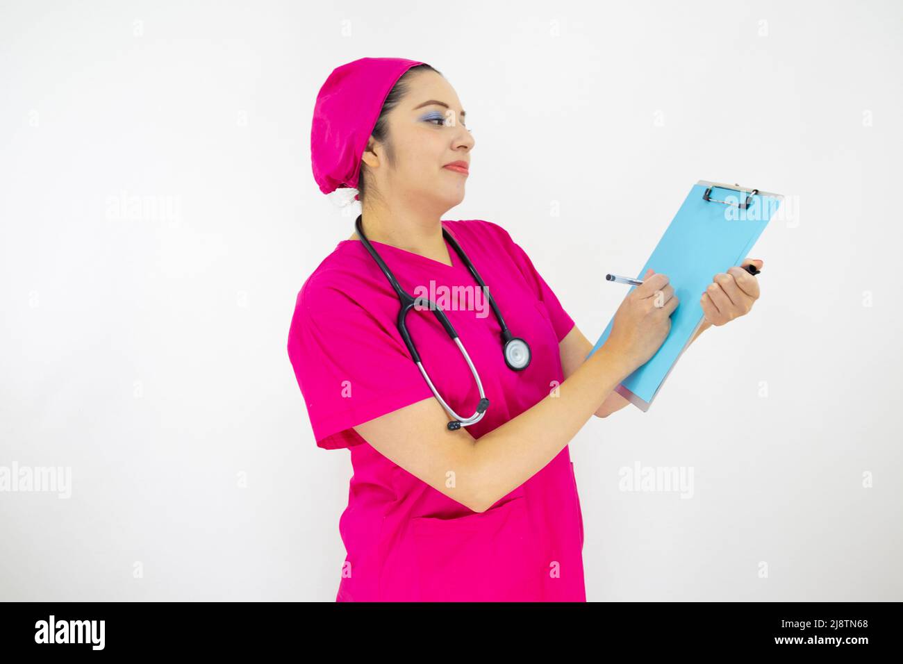 Schöne Frau medizinische Assistentin, trägt Uniform und rosa OP-Kappe, Stethoskop am Hals, hält Zwischenablage mit Ergebnissen, auf weißem Hintergrund Stockfoto