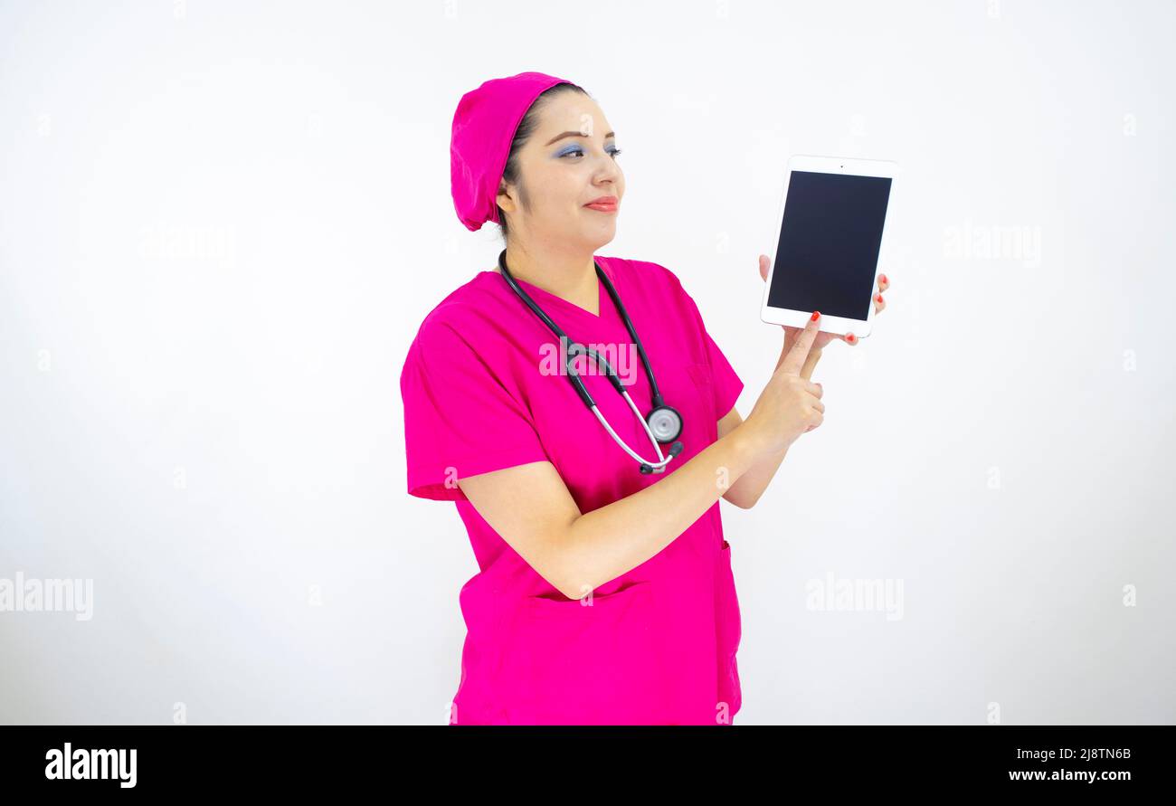 Schöne Frau medizinische Assistentin, trägt rosa Uniform und rosa OP-Kappe, Stethoskop, mit dem Tablet, um Ergebnisse auf weißem Hintergrund anzuzeigen Stockfoto
