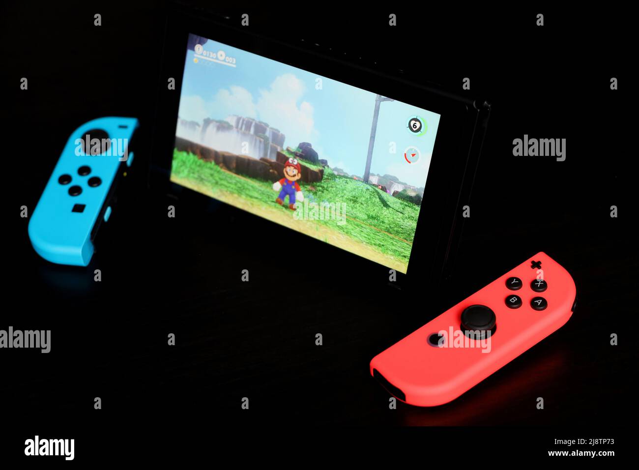 Nintendo Switch mit Super Mario Odyssey auf einem Bildschirm, selektiver Fokus. Videospielkonsole im Handheld-Modus mit der Joy-Con auf schwarzem Hintergrund Stockfoto