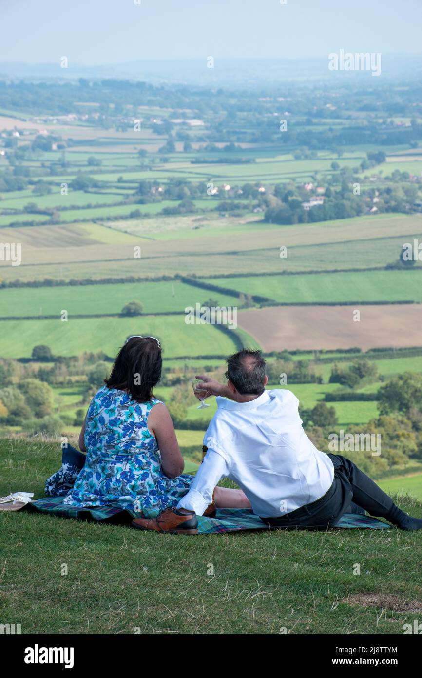 Ein Picknick für Paare mittleren Alters am Glastonbury Tor mit Blick auf die Somerset-Ebenen Stockfoto