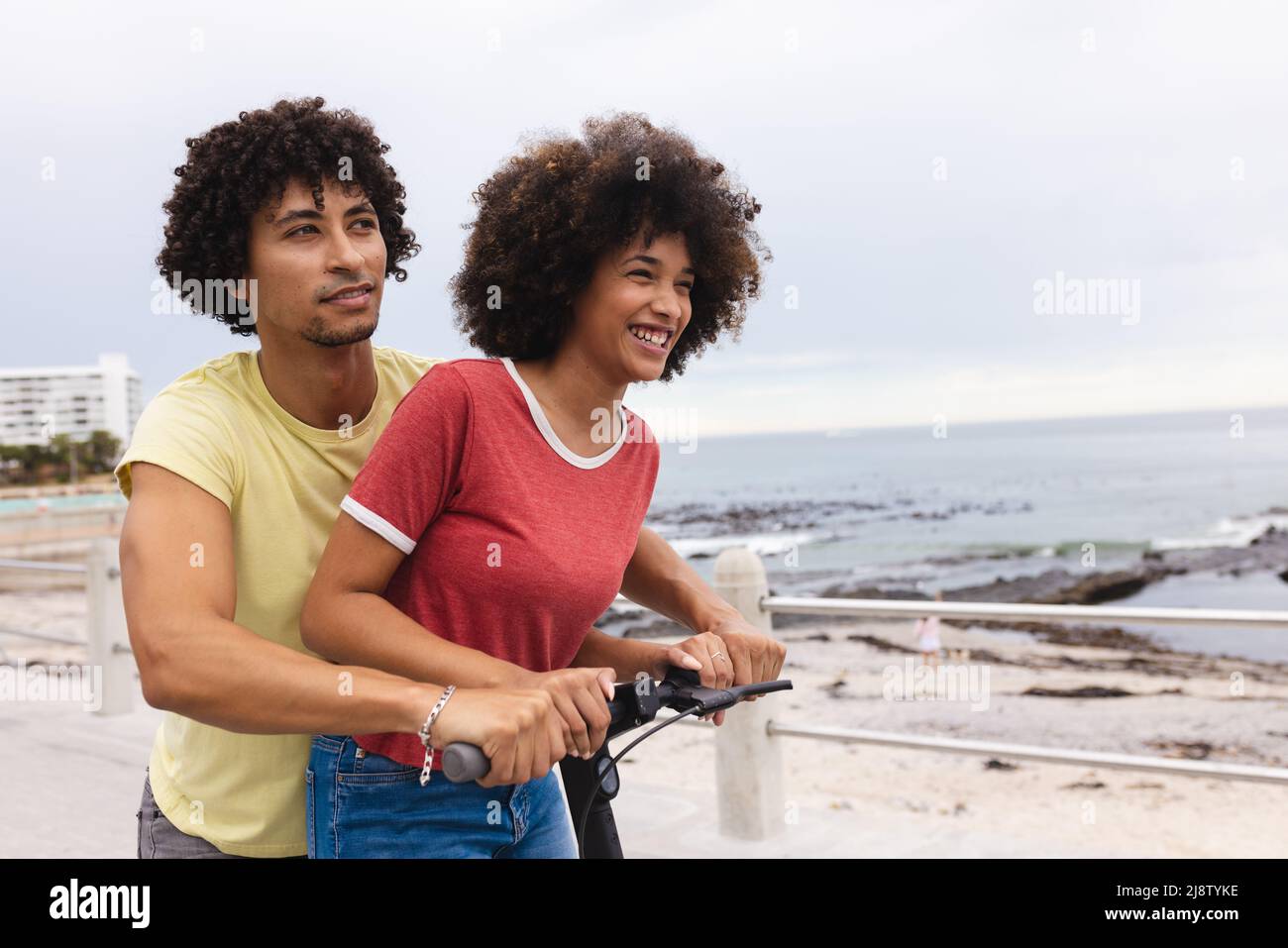 Liebende junge afro afroamerikanische Paar genießen Push Scooter Fahrt am Strand, kopieren Raum Stockfoto