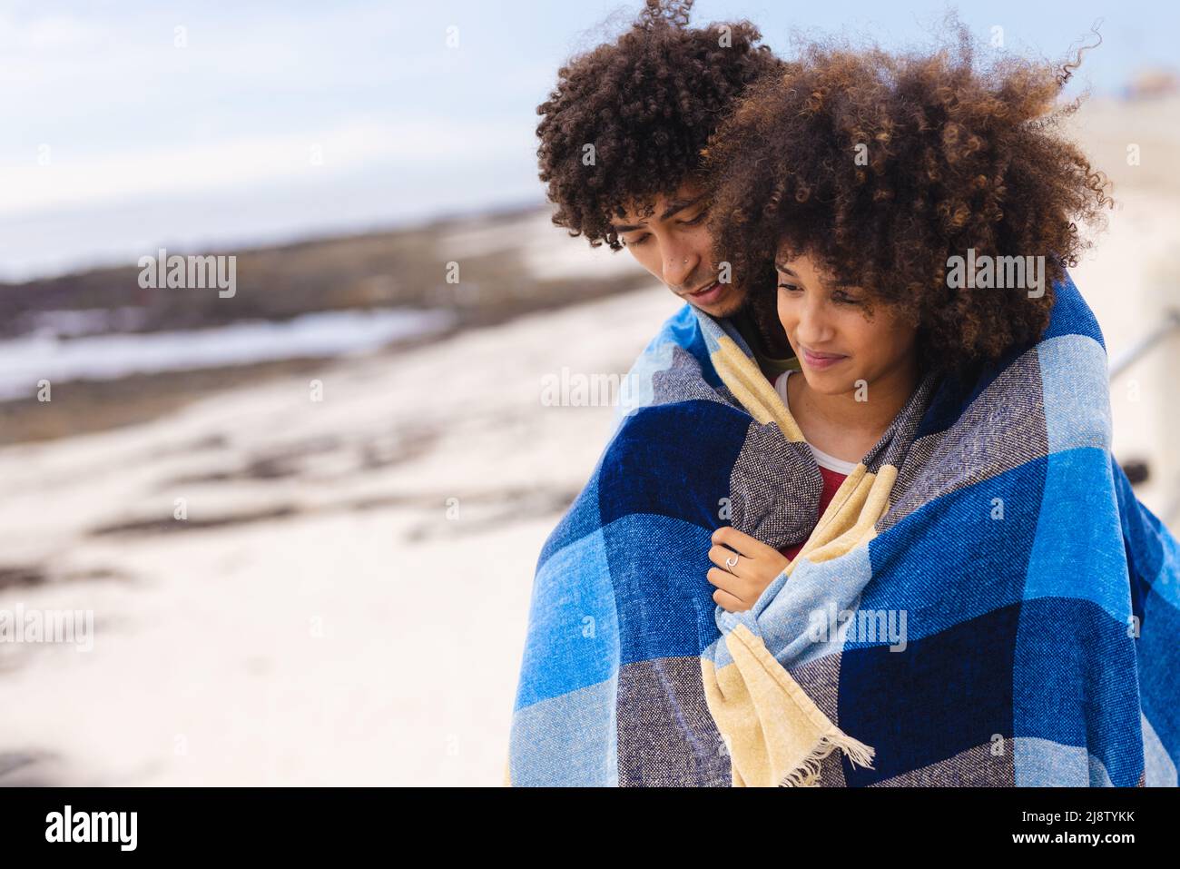 afroamerikanisches junges Paar, das am Strand in eine Decke gehüllt wurde Stockfoto