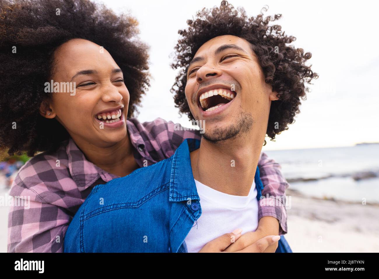 Verspieltes afro afroamerikanisches junges Paar, das am Strand genießt Stockfoto
