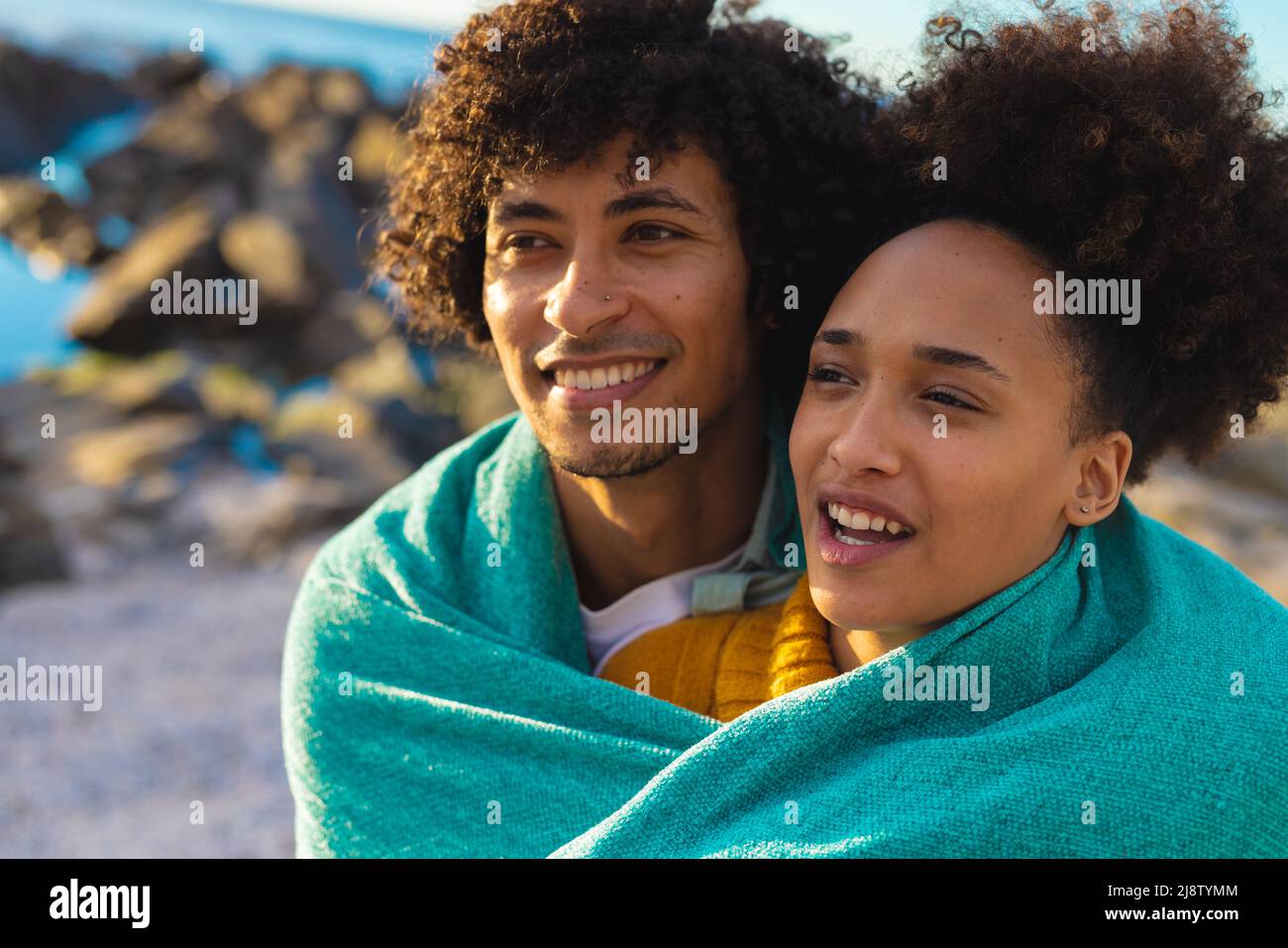 afroamerikanisches junges Paar, das in eine Decke gehüllt und auf den Strand blickt Stockfoto