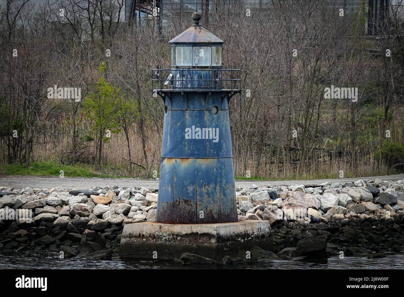 Ein alter Leuchtturm liegt direkt vor einem Hafen von Connecticut, der mit Rost und verblassten Farben bedeckt ist Stockfoto