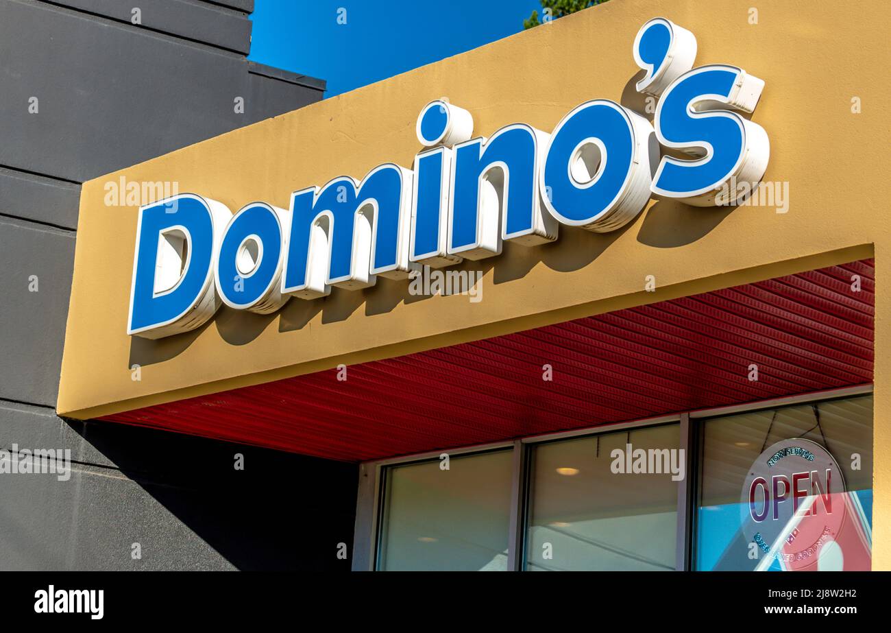 Domino's Außenfassade-Marke und Logo-Beschilderung in blauen Buchstaben über reflektierenden Fenstern an einem sonnigen Tag mit klarem blauen Himmel. Stockfoto